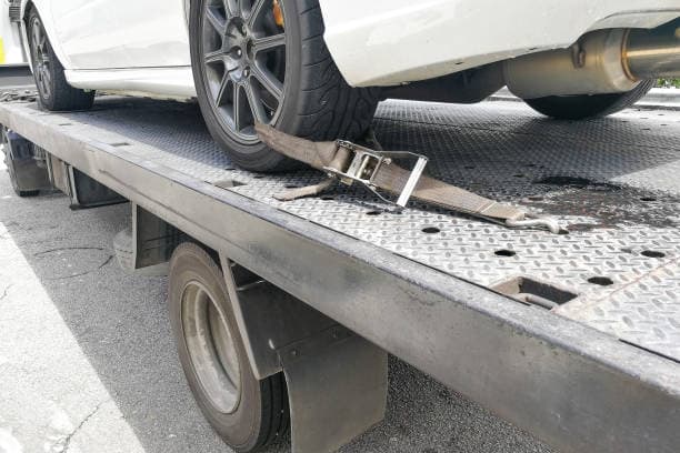 Vehicle wheel secured to a flatbed with a transport strap