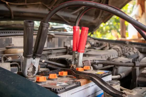 Positive and negative battery clamps connected under a car bonnet