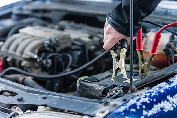 Technician connecting a jump-start clamp to a vehicle battery
