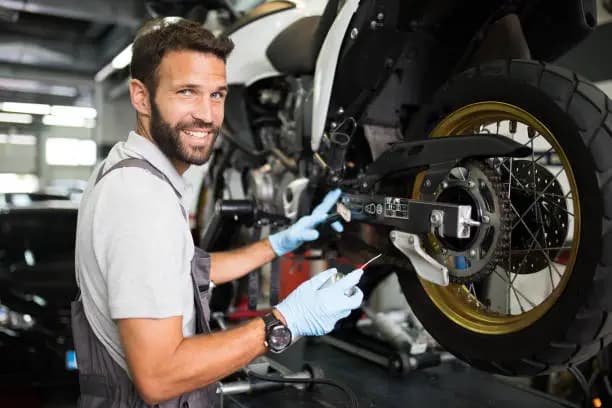 Motorcycle technician inspecting a bike wheel and drivetrain